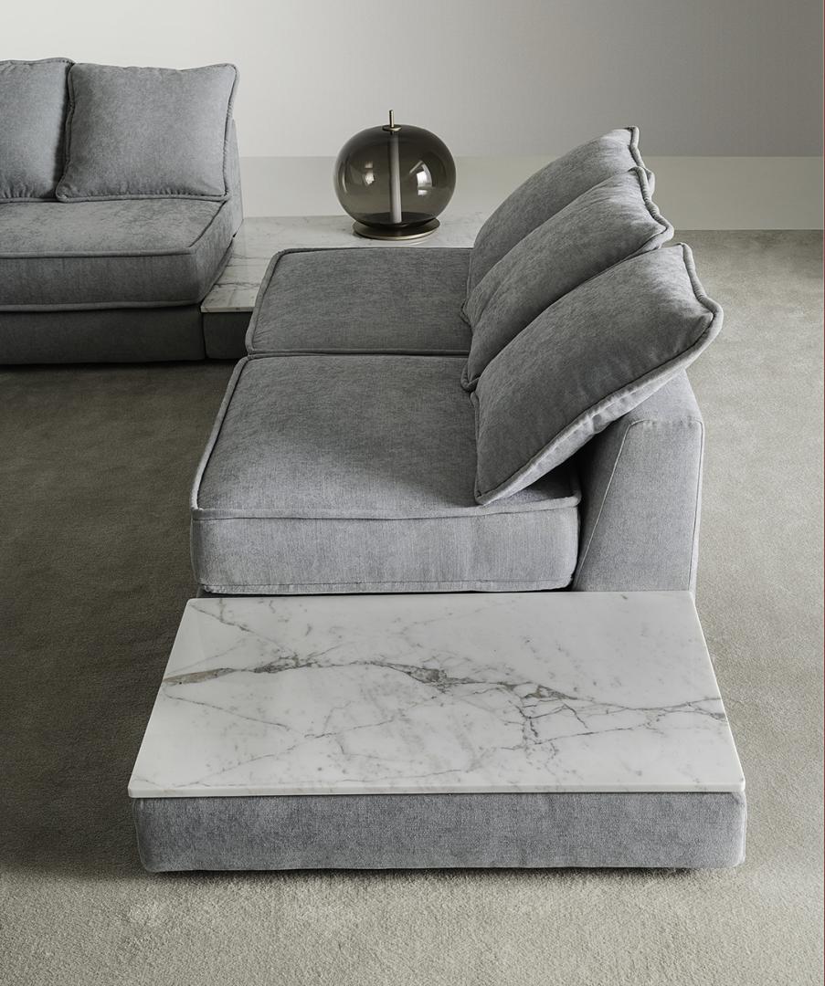 Interior view of a gray sectional sofa with plush cushions and a white marble coffee table by Casamilano
