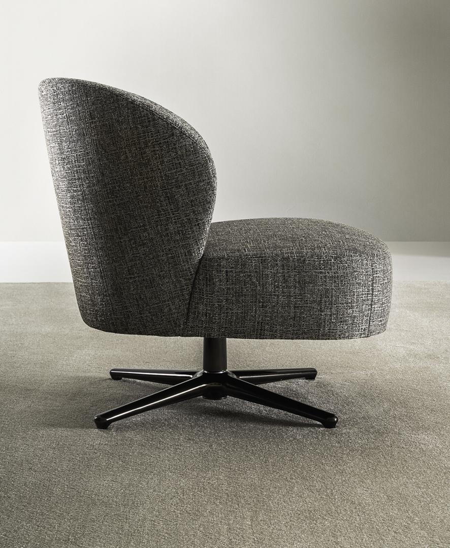 Side view of the Dhora Slim armchair by Casamilano. Gray upholstery, curved back, black metal base, modern swivel accent chair