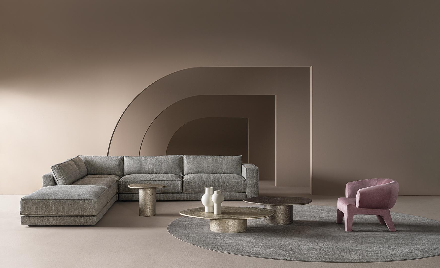Modern living room featuring a gray sectional sofa, round coffee tables, a gray rug, and a pink Casamilano Lola armchair.