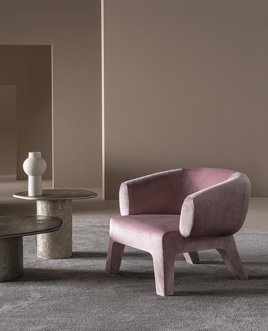 A modern living space featuring a pink velvet Casamilano Lola armchair and textured side tables