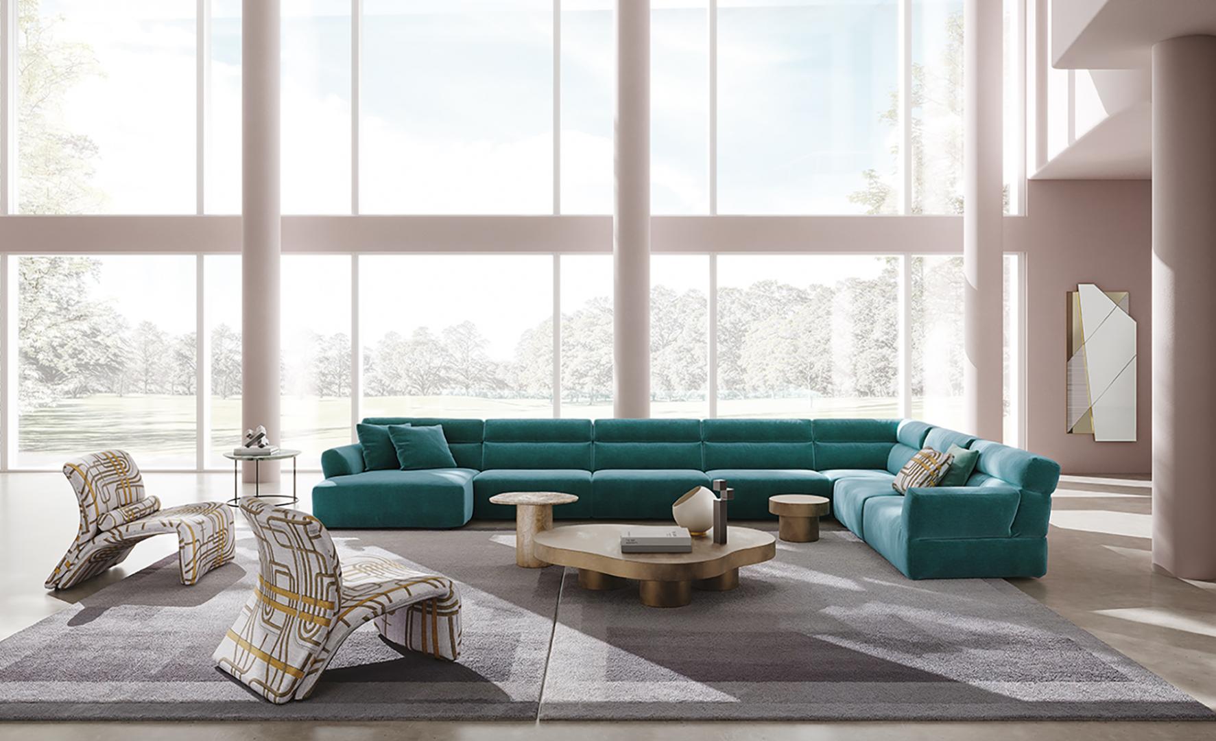 Modern living room featuring a teal sectional sofa, geometric accent chairs, and a sculptural gold coffee table by Casamilano. Natural light fills the open space