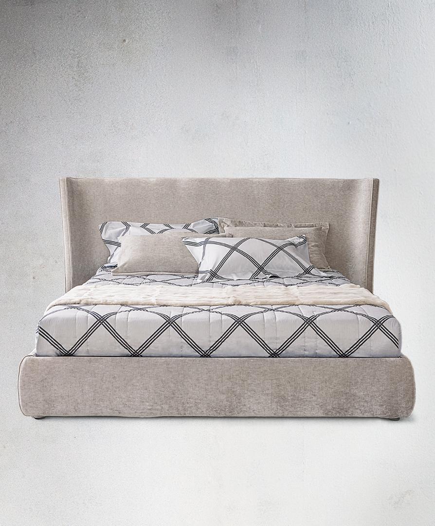 Front view of the Casamilano Vanity upholstered platform bed with wingback headboard, decorative pillows, and patterned comforter