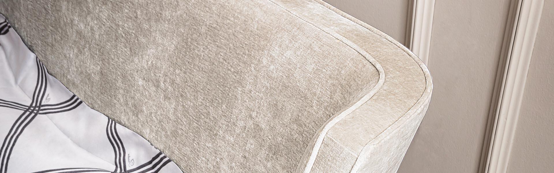 Close-up of the Casamilano Vanity upholstered headboard in beige velvet, showcasing its curved silhouette and luxurious detailing