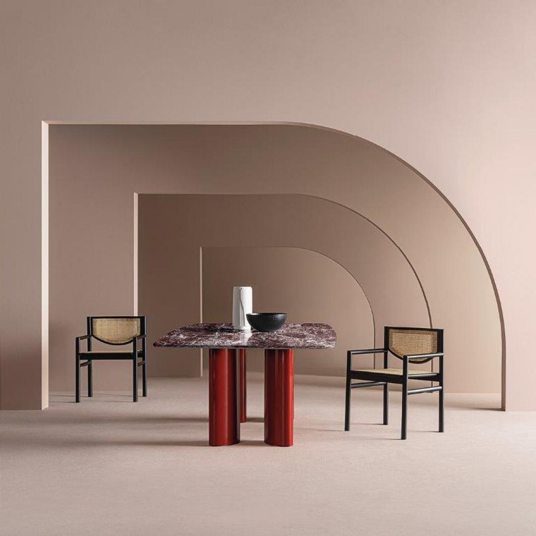 Modern dining room featuring the Casamilano Arne dining table with a marble top and red legs, paired with elegant cane chairs