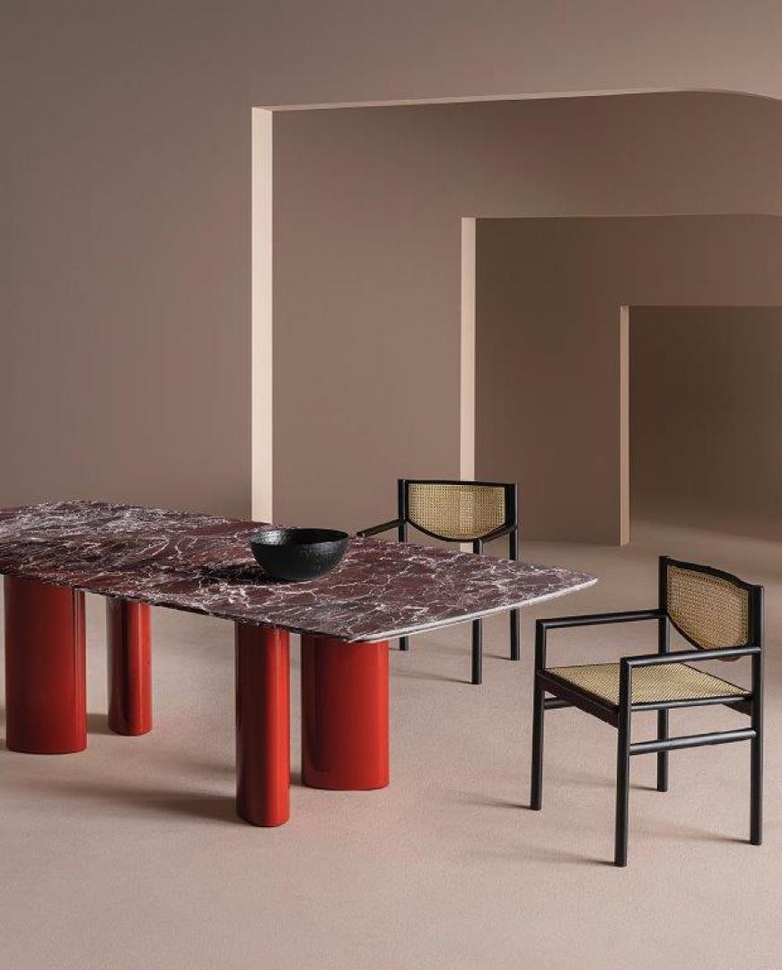 Interior of a modern dining room featuring the Casamilano Arne dining table with a red marble top, paired with black framed woven chairs
