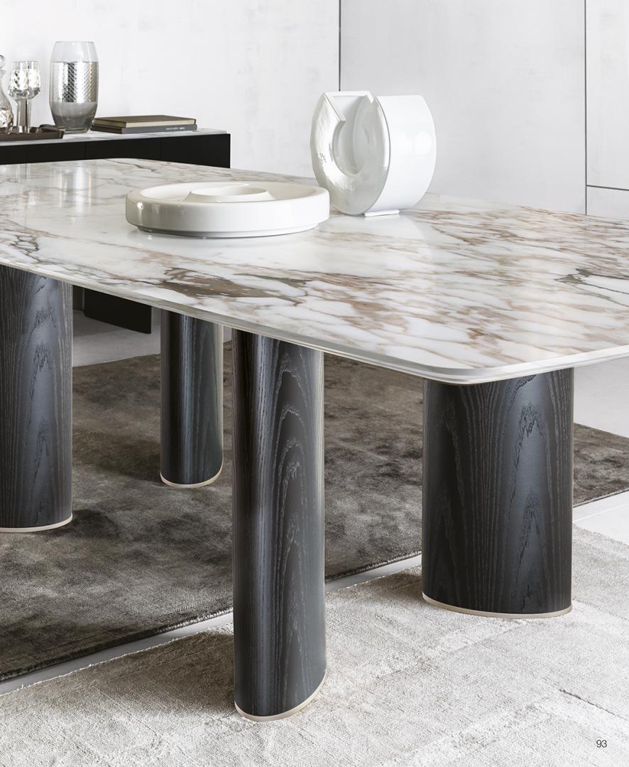 Close-up of Casamilano Arne dining table with marble top, dark wood legs, and white ceramic decor. Modern luxury for sophisticated dining