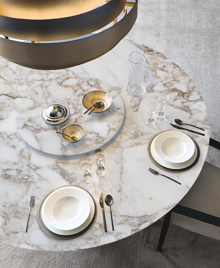 Overhead view of Casamilano's Arne dining table, a round marble table set with luxury dinnerware and glassware for formal dining