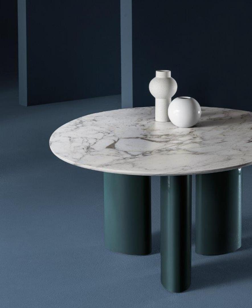 Casamilano Arne dining table featuring a round marble top, teal cylindrical legs, and decorative vases. Perfect for modern dining rooms