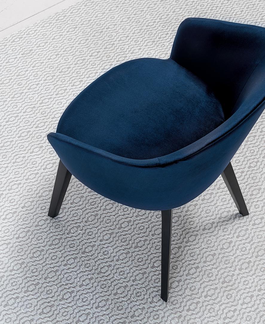 Close-up of the Casamilano Shirley dining chair in blue velvet on a patterned rug. Modern accent chair for stylish home decor.
