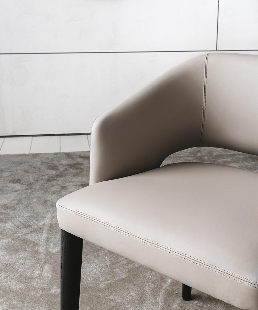 Close-up of the Elsa dining chair by Casamilano, featuring light leather upholstery and dark wooden legs, perfect for modern interiors