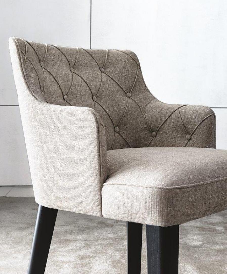 Close-up of the Casamilano Royale Capitonné accent chair. Upholstered design with tufted back, armrests, and sturdy legs. Perfect living room furniture