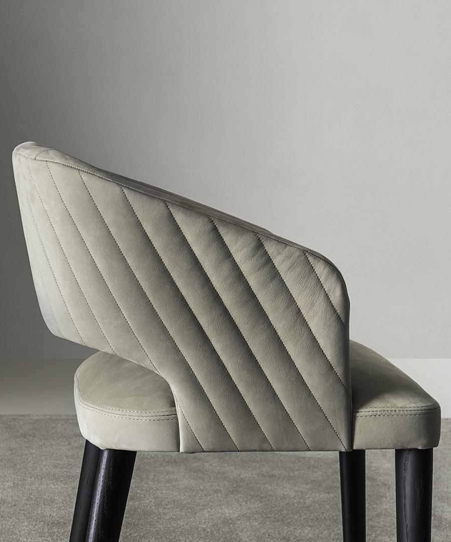 Close-up of quilted leather dining chair back and seat on carpet.