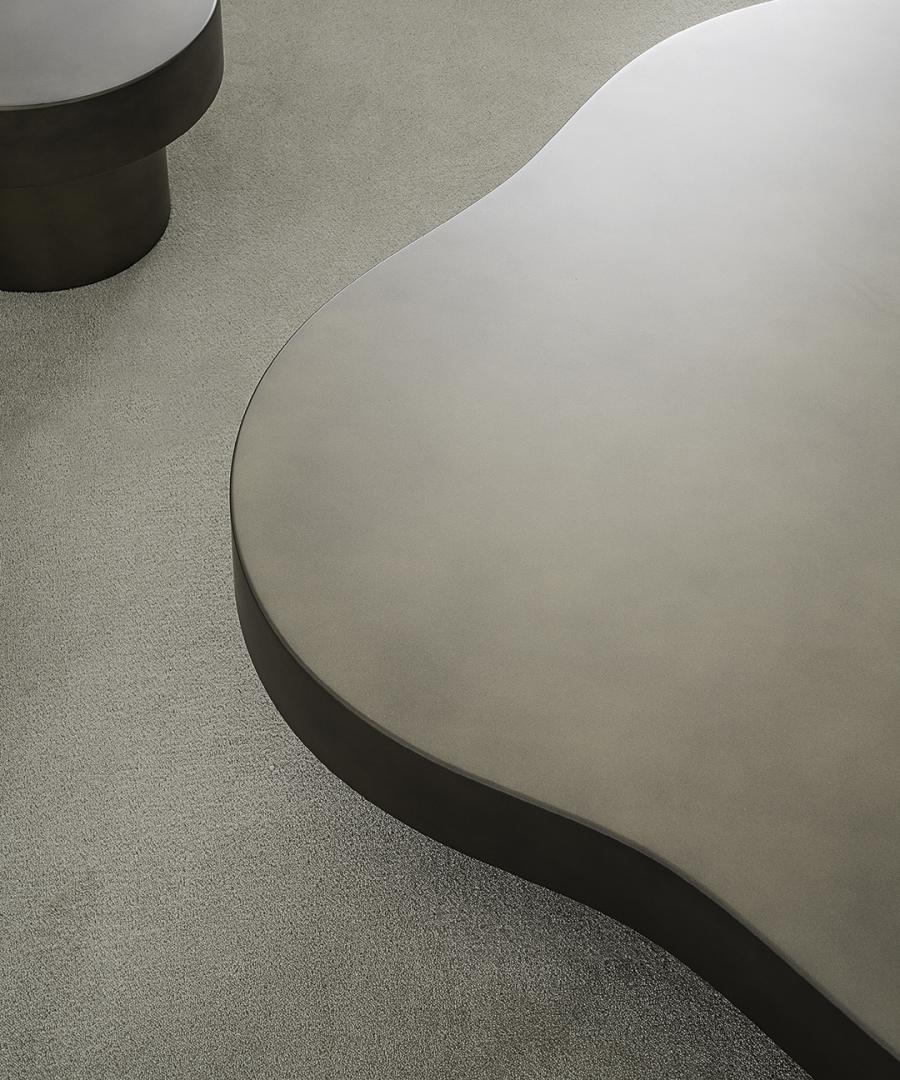 A high-angle shot of a modern living room featuring a Casamilano Nuvola coffee table with a round side table on a textured carpet
