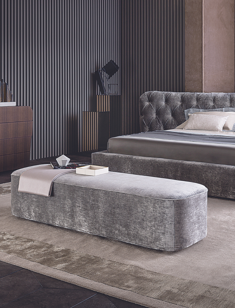 A luxurious bedroom featuring an upholstered bed, velvet bench, modern dresser, and the Casamilano Hyatt 160 Pouf.