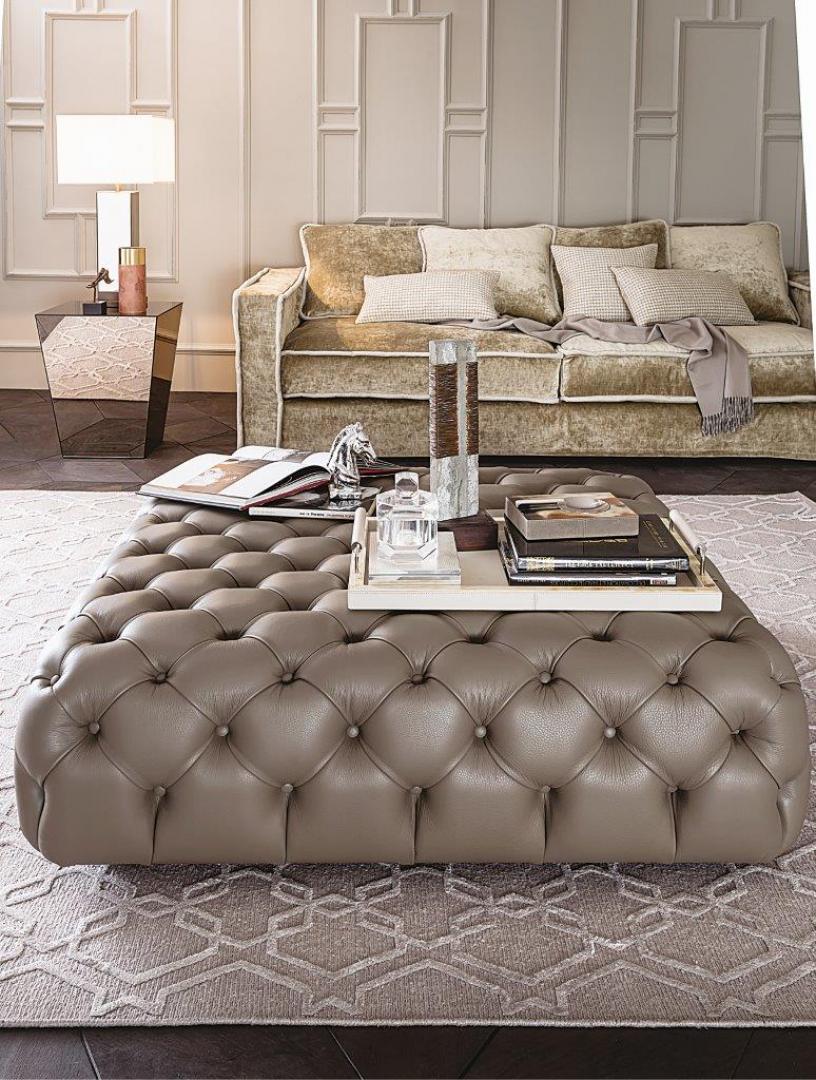 Elegant living room with a tufted Casamilano Hyatt 120 pouf, velvet sofa, mirrored side table, and modern lamp.