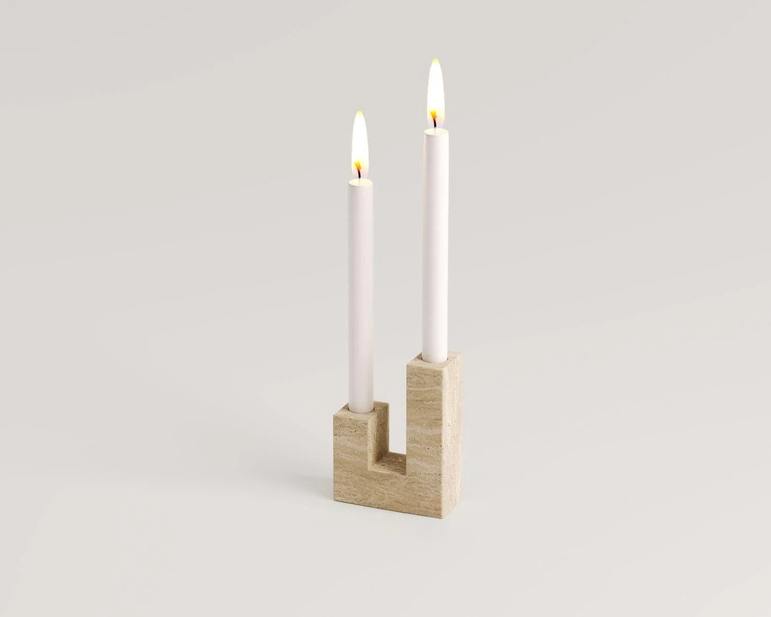 Travertine U-shaped candle holder with two white candles lighting
