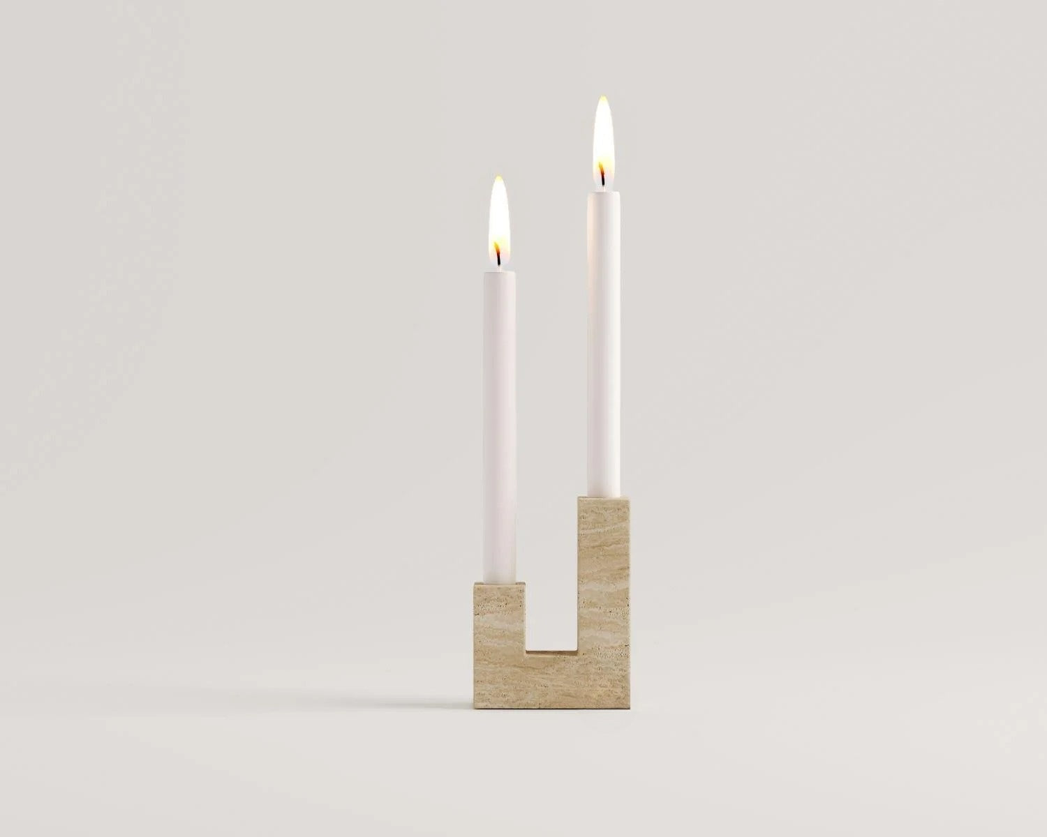Minimalist travertine candlestick with two lit white candles decor