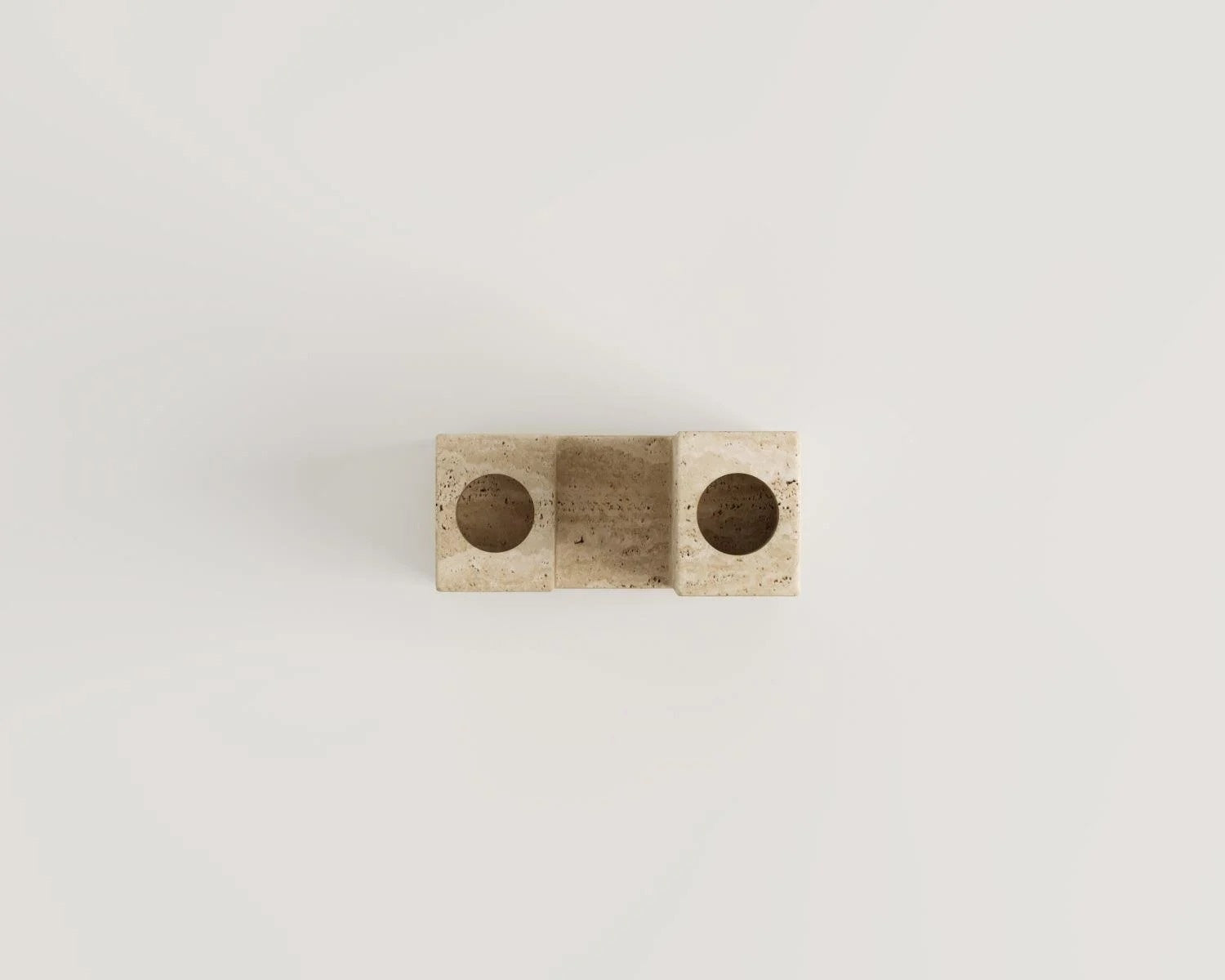 Travertine decor piece with two circular openings against white background