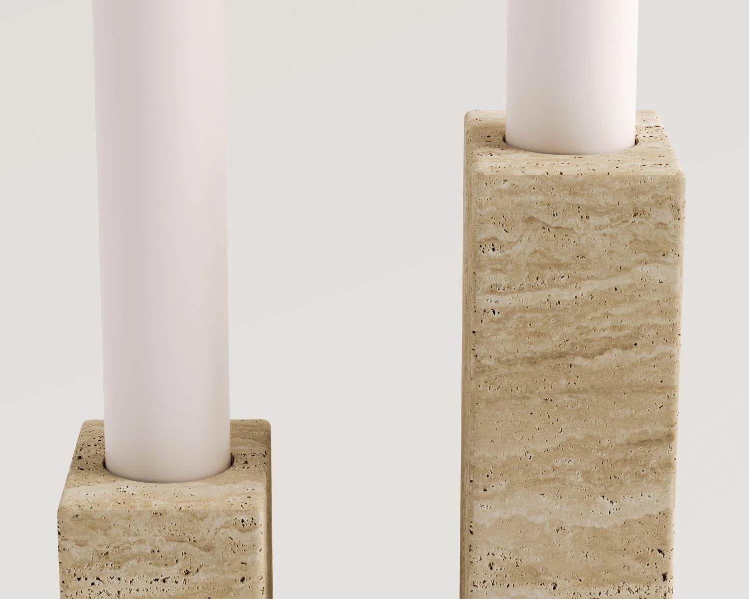 Close up view of two travertine candle holders with white candles. Travertine candle holders, white candles, home decor, modern furniture, stone accessories.
