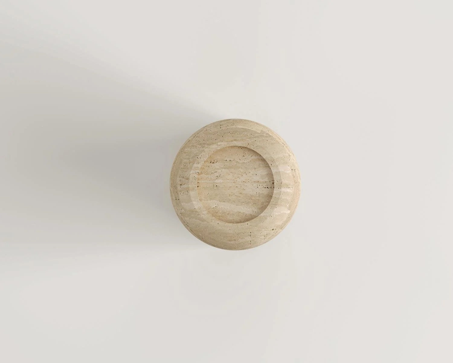 Overhead view of round travertine decor piece on white surface