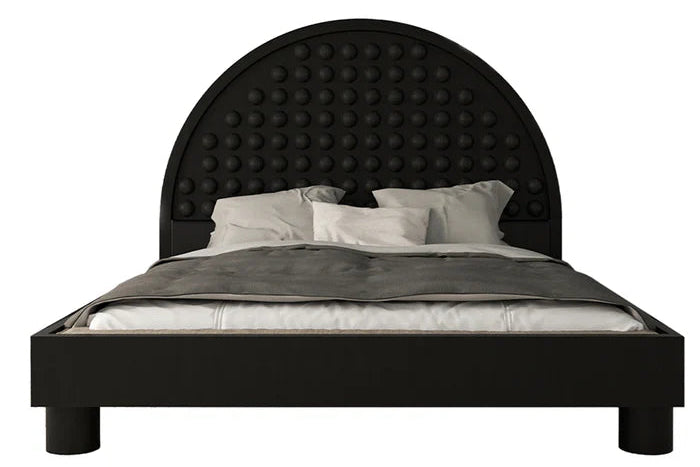 Black bed with arched headboard and circular detail against white background. Black bed frame, arched headboard, circular detail, white bedding, gray throw, white background. Black bed, arched headboard, circular detail, white bedding, gray throw, white background.