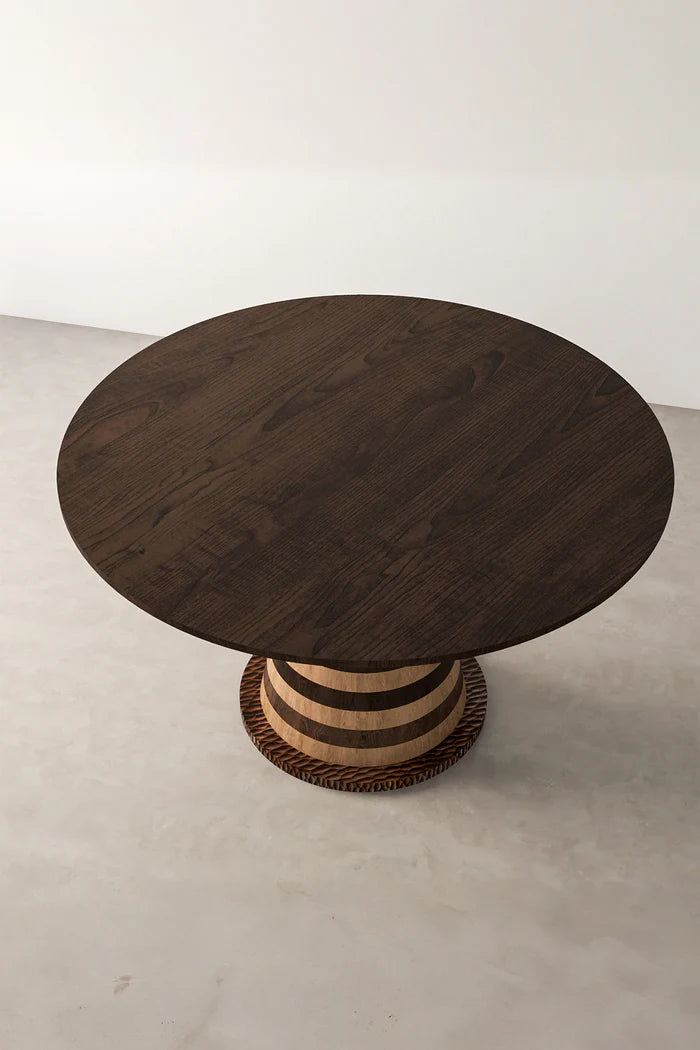 Overhead view of round wood dining table with striped base. Dark wood table top, light wood base with dark wood stripes. Dining table, wood furniture, round table, pedestal base, modern dining, interior design, home decor, furniture photography.