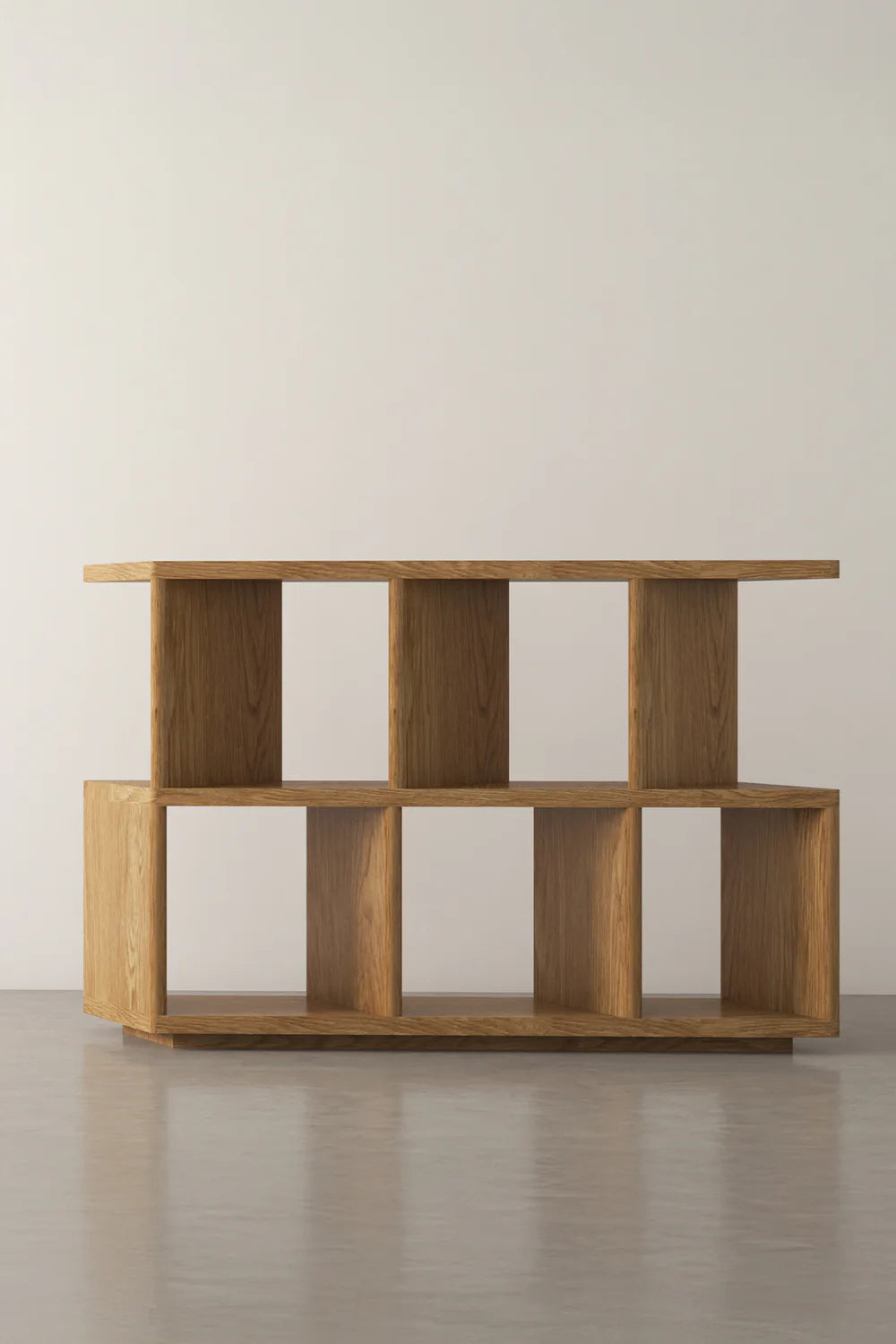 Wood shelving unit with open cubbies on concrete floor against white wall.