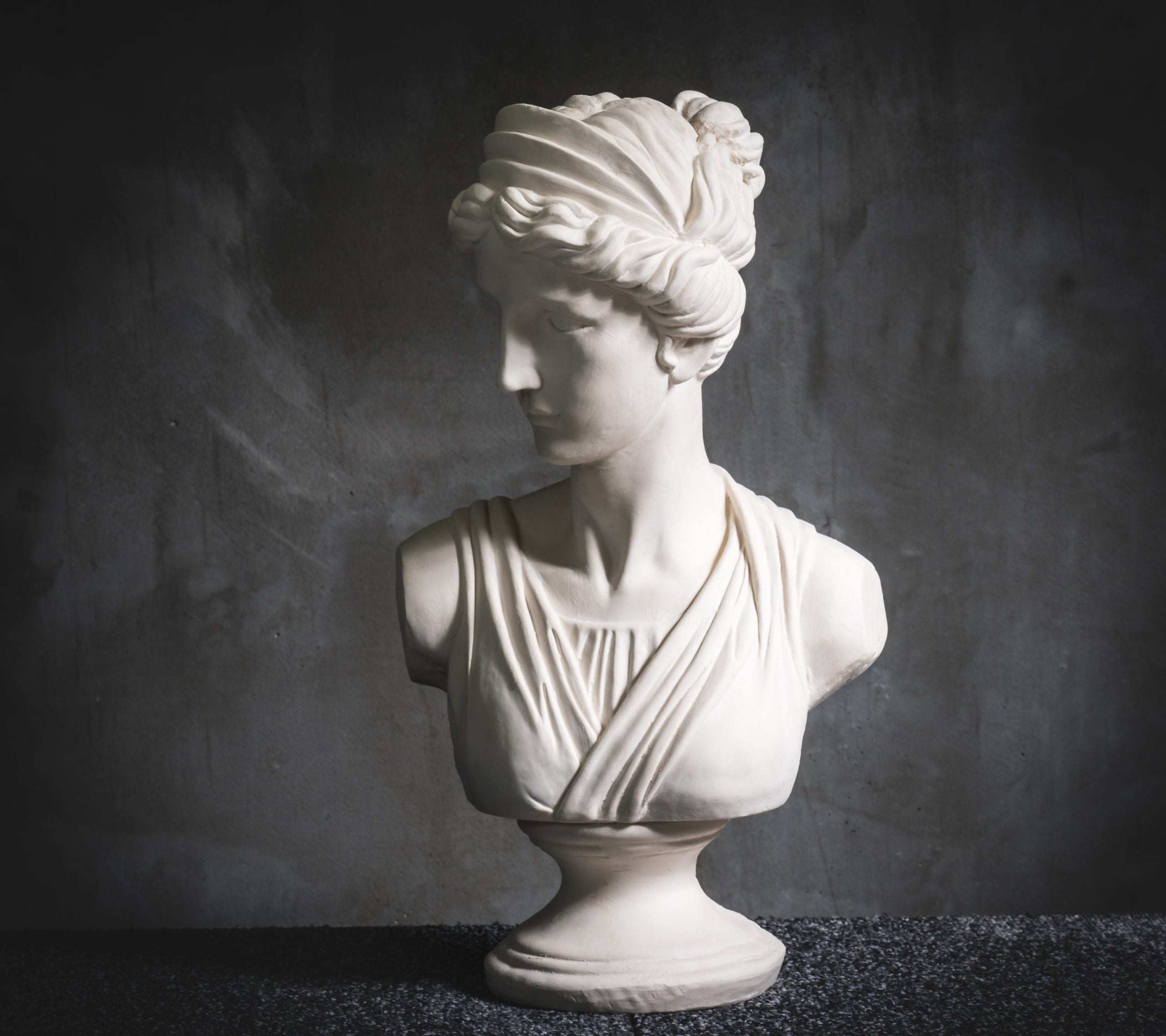 White plaster female bust sculpture on dark background