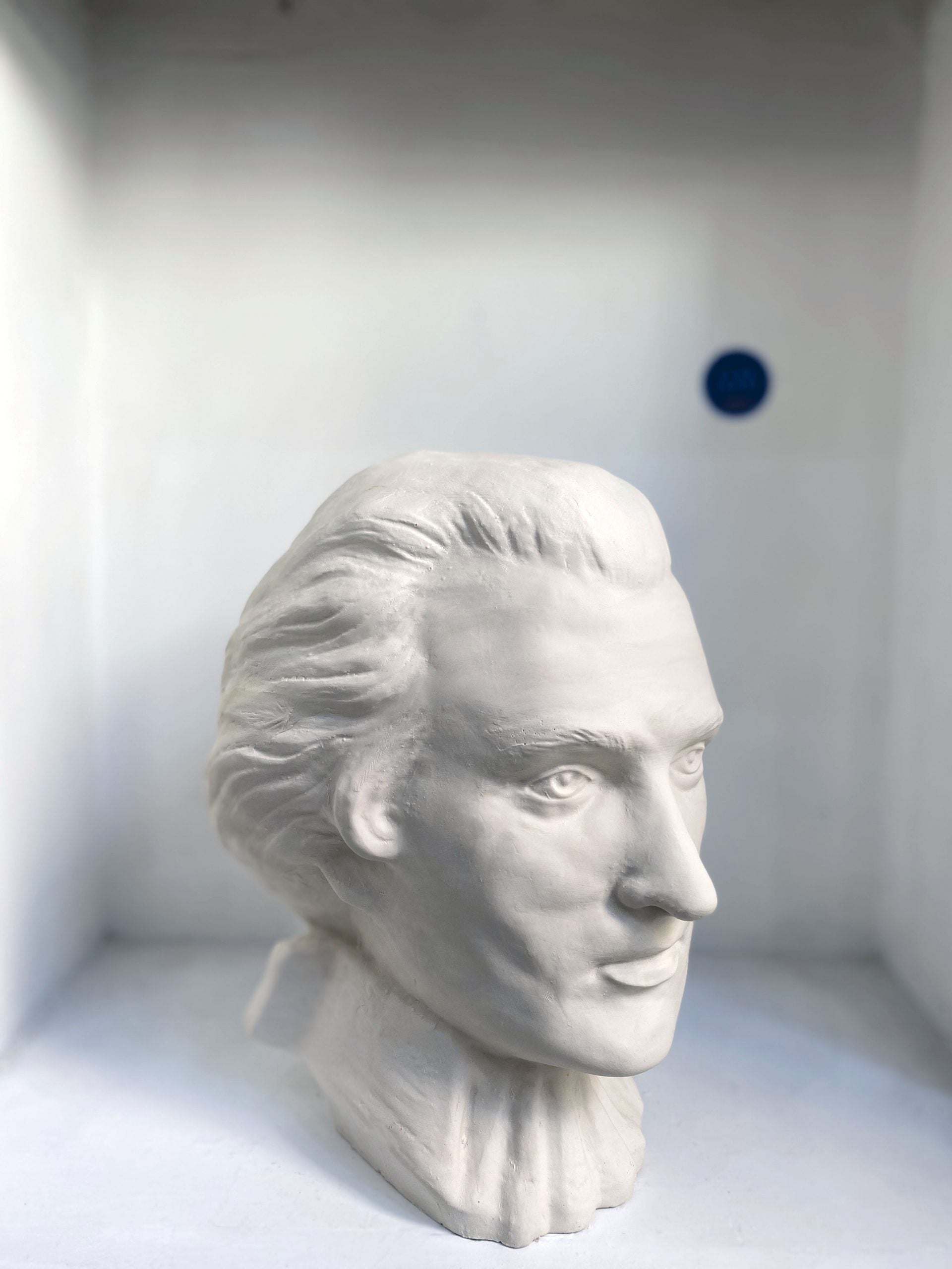 White plaster bust sculpture of a man's head in profile view.