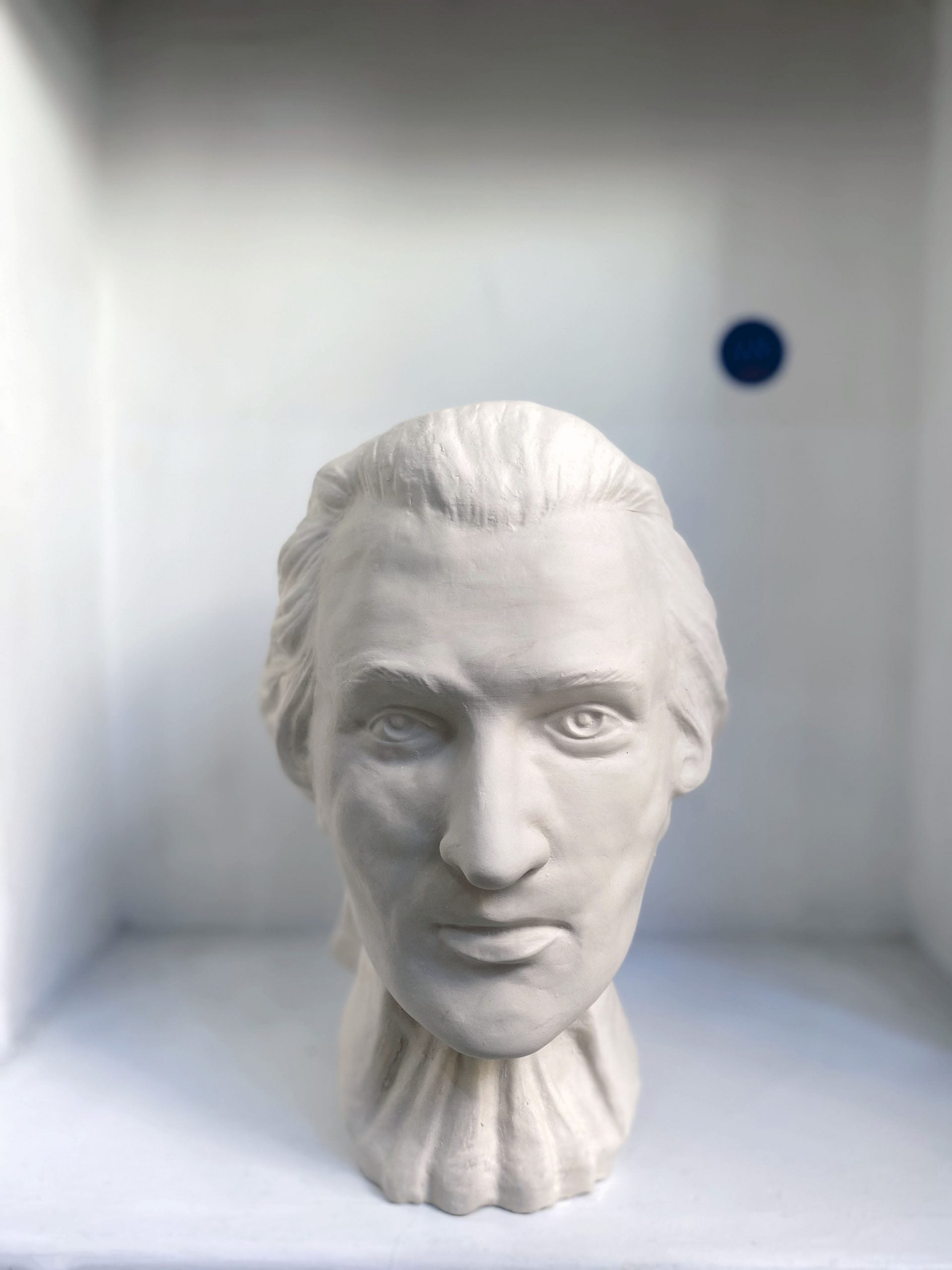 White plaster bust sculpture of a man's head and neck.