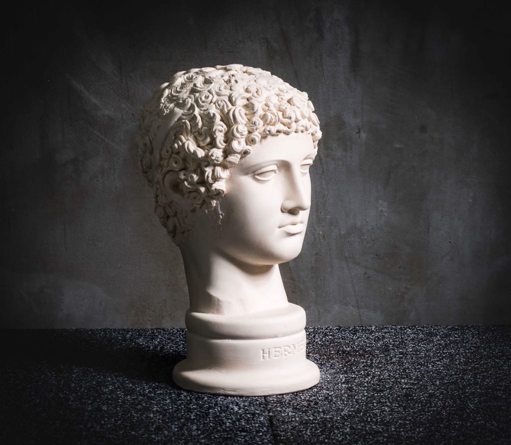 White plaster head sculpture of Hermes on dark surface