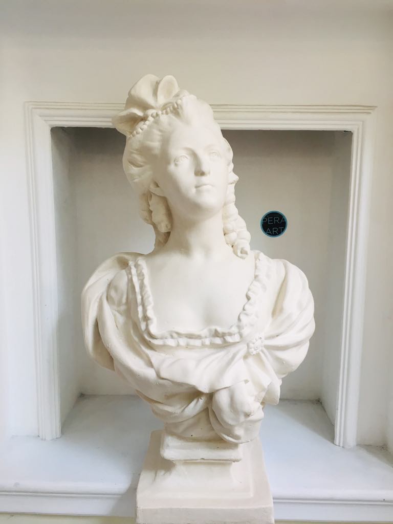 White female bust sculpture on pedestal in niche wall decor.
