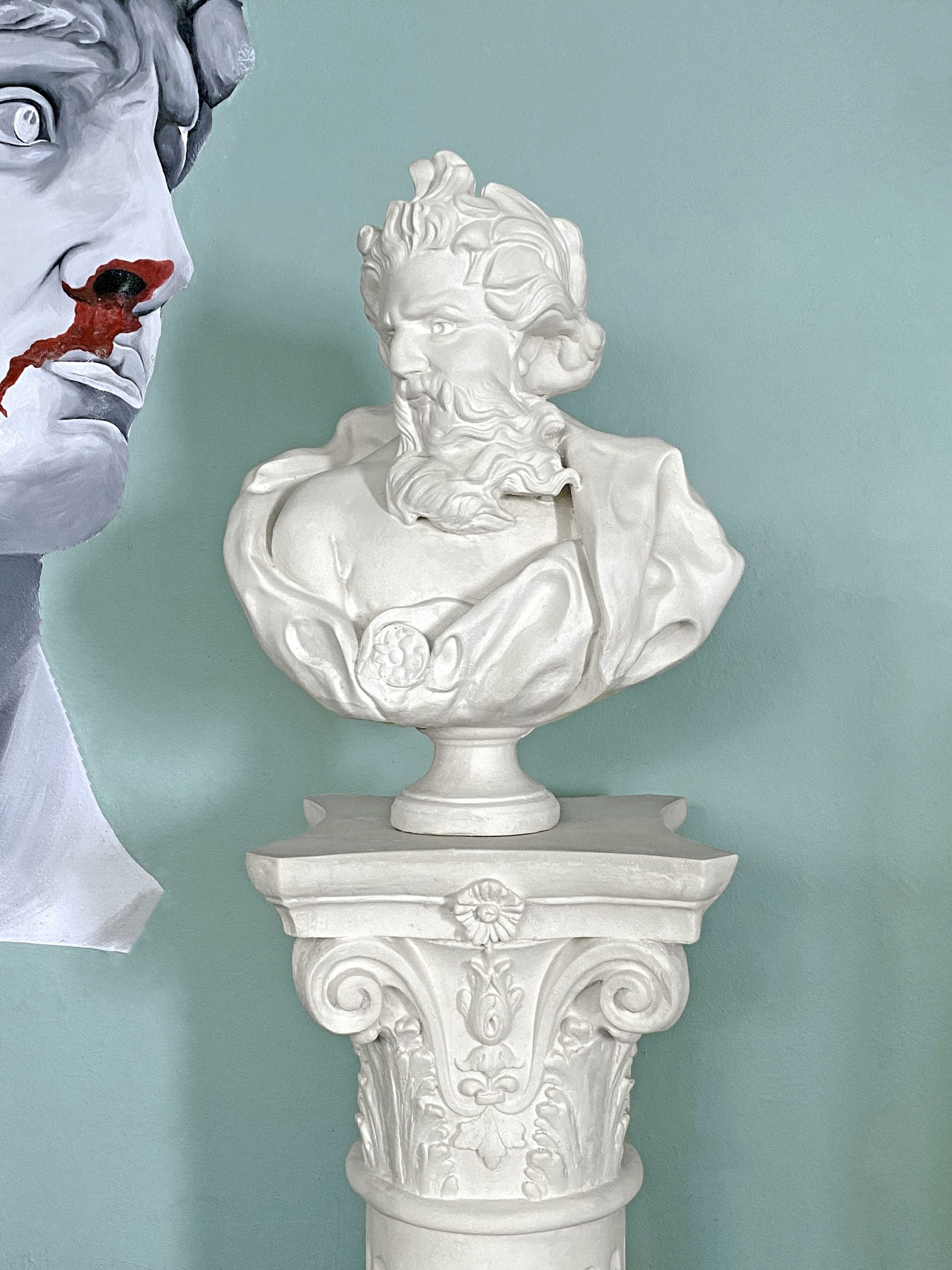 White bust sculpture on pedestal against blue wall
