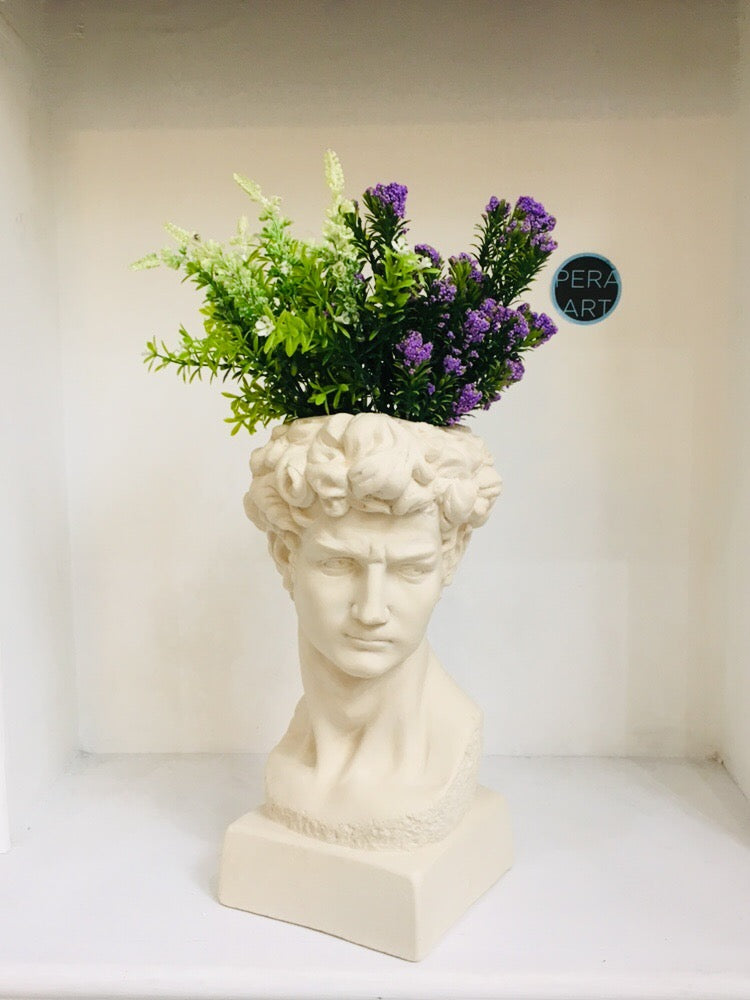 White plaster bust planter with green and purple artificial flowers