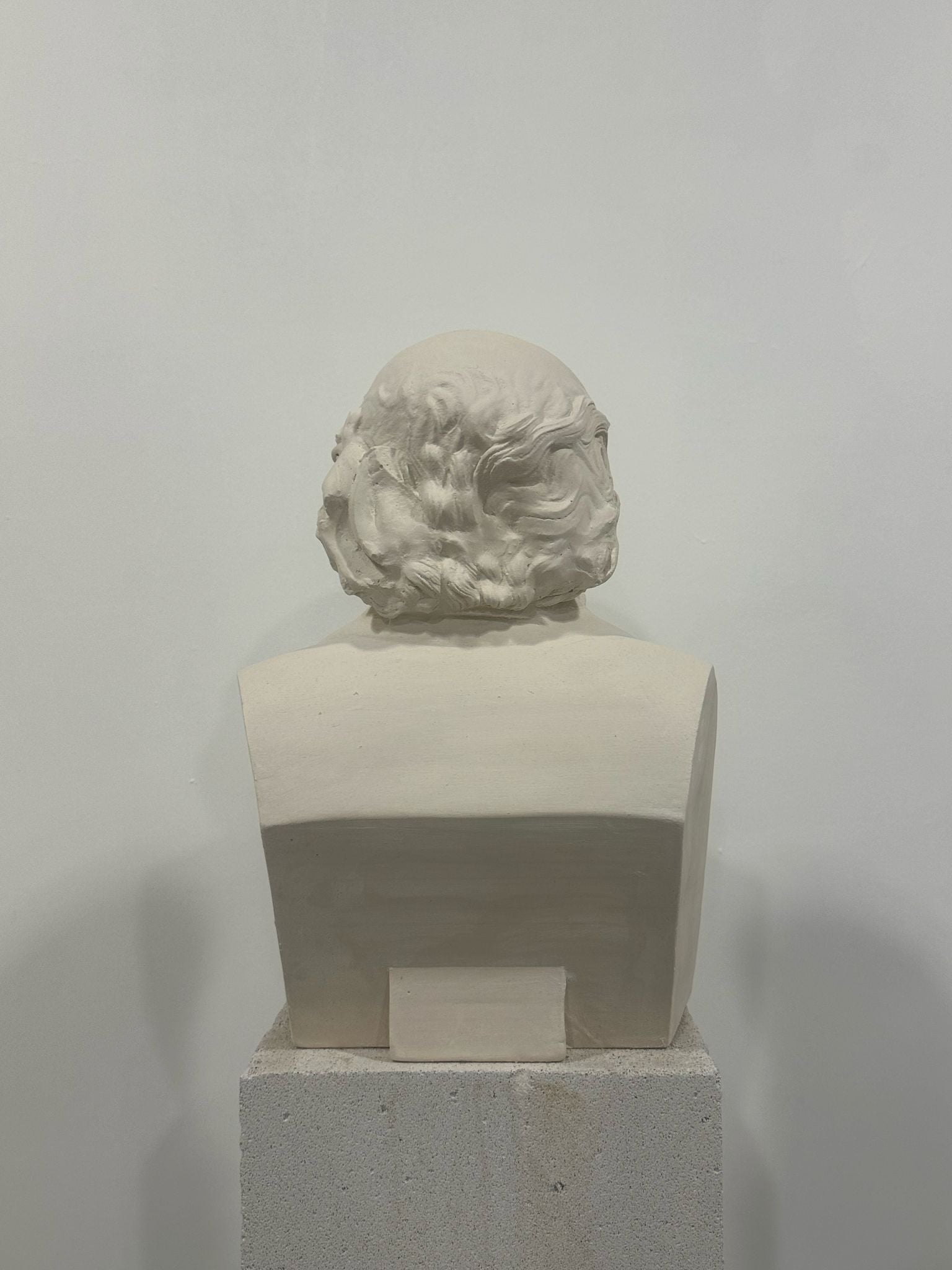 White plaster bust sculpture back view on concrete pedestal