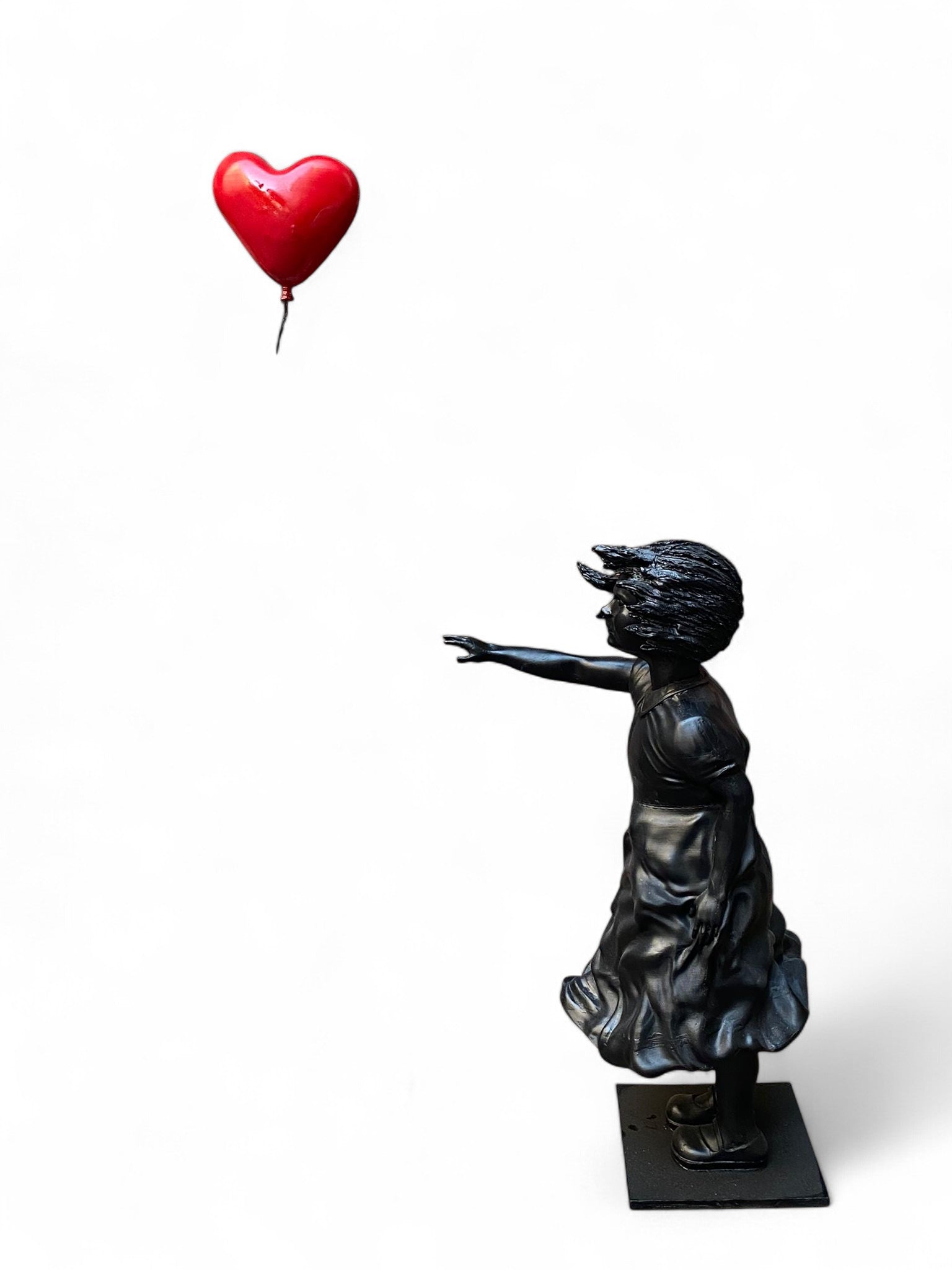 Black girl sculpture reaching for red heart balloon decor