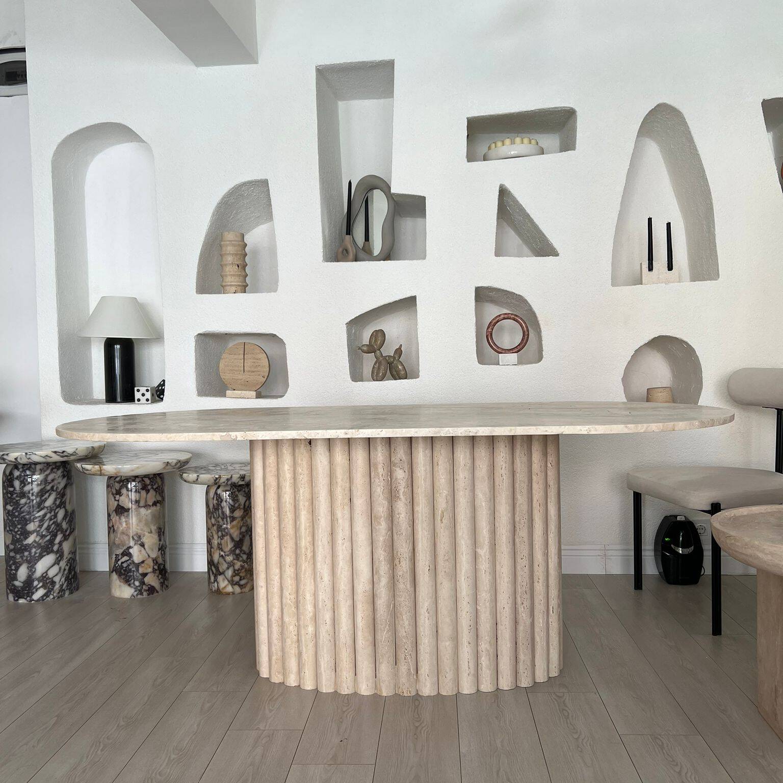 Modern living space with Luzione Porphyry travertine dining table, marble side tables, and minimalist decor. Interior design with stone furniture