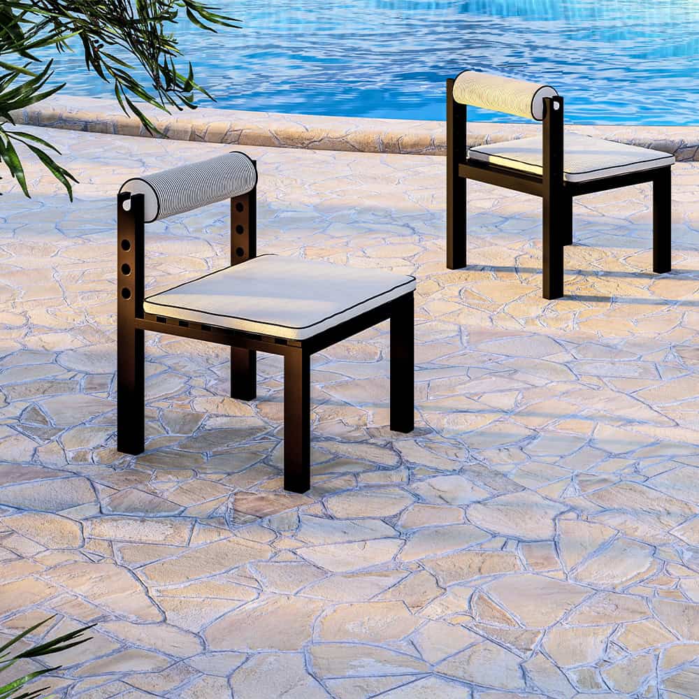 Two modern outdoor chairs on a stone patio by a pool.