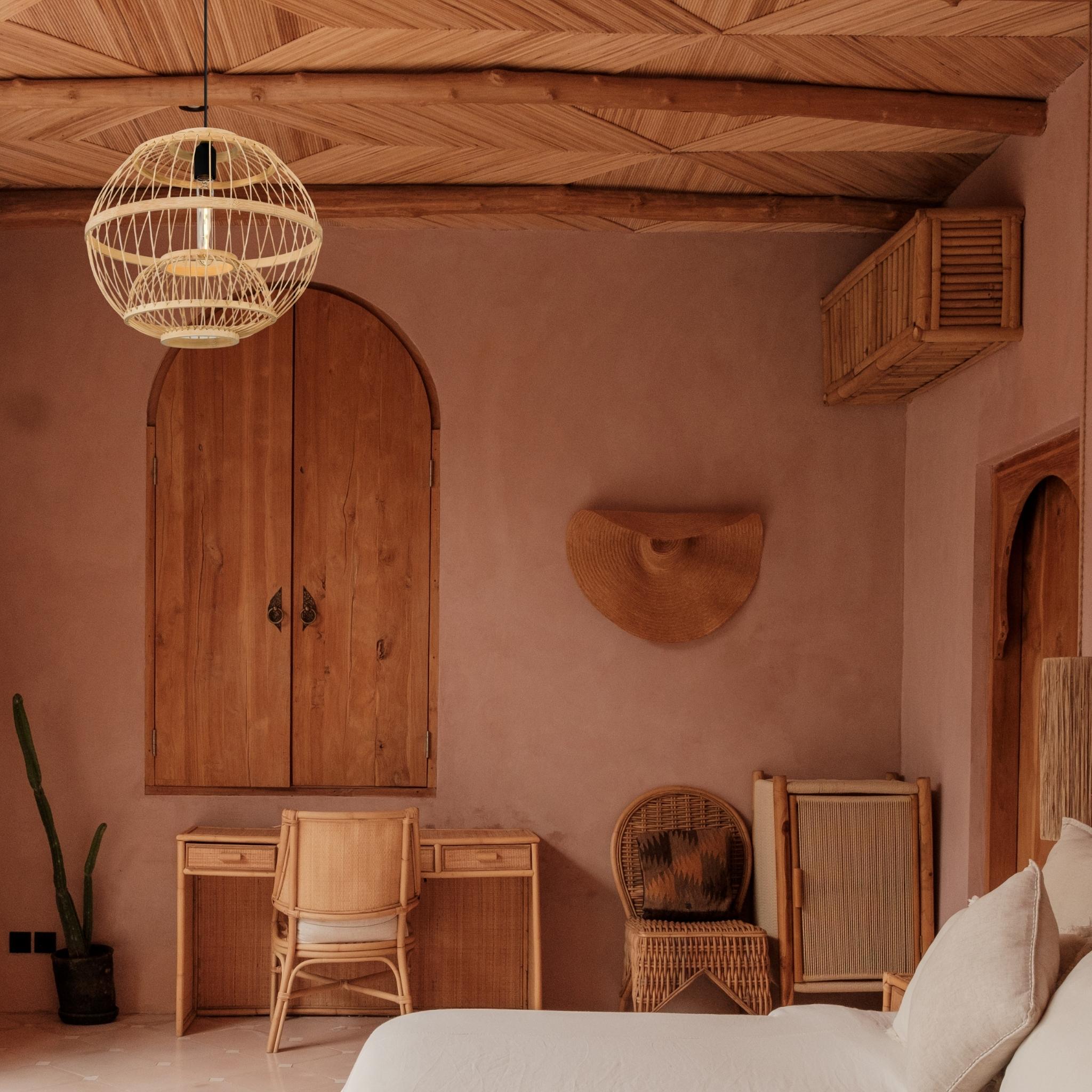Bohemian bedroom featuring rattan furniture, wood ceiling, and terracotta walls.