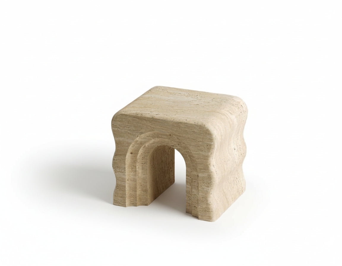 Full view of a Luzione travertine side table with wavy edges against a white background. Modern, minimalist stone furniture for living room or bedroom decor