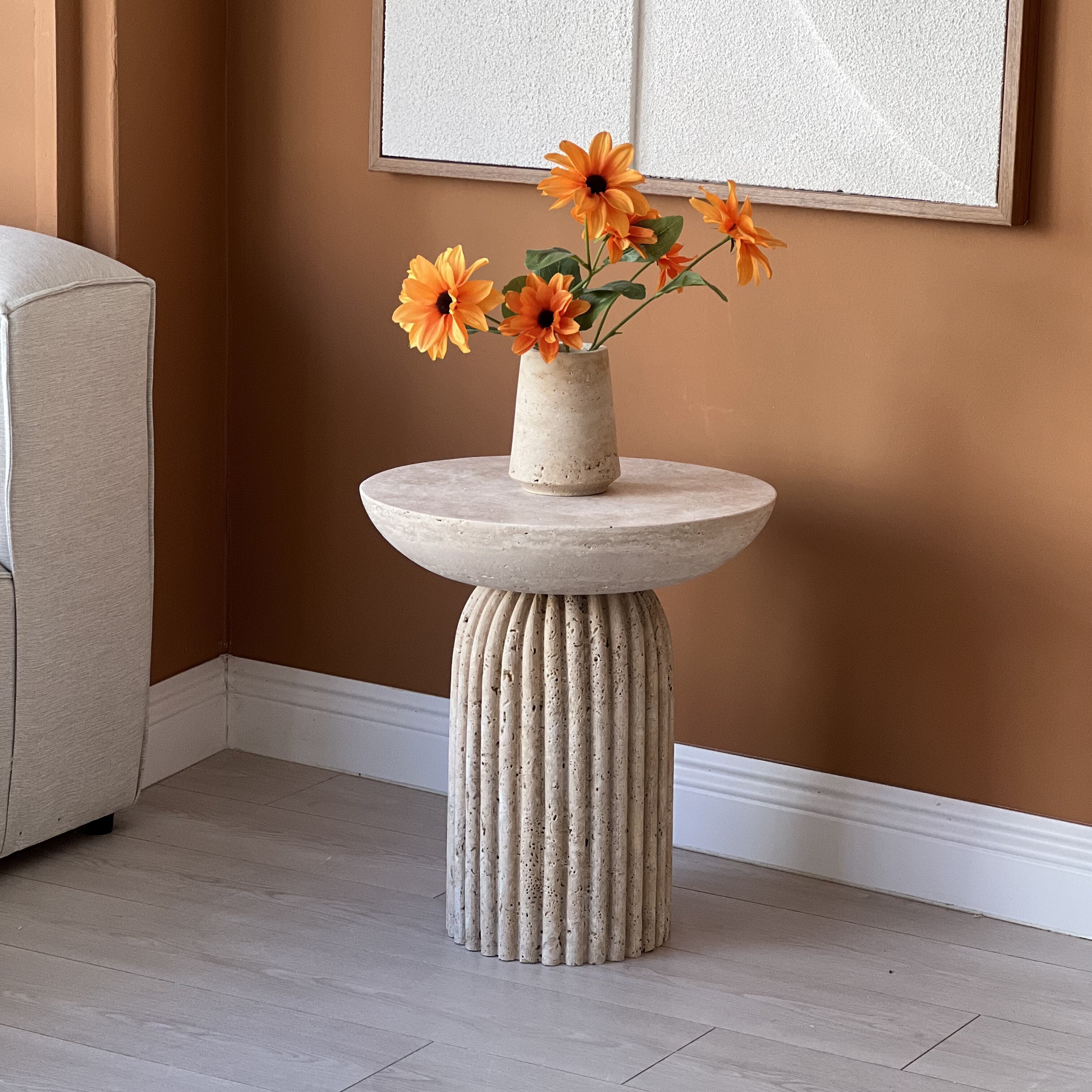 Modern living room featuring a Luzione travertine side table with a cylindrical, fluted base and round tabletop