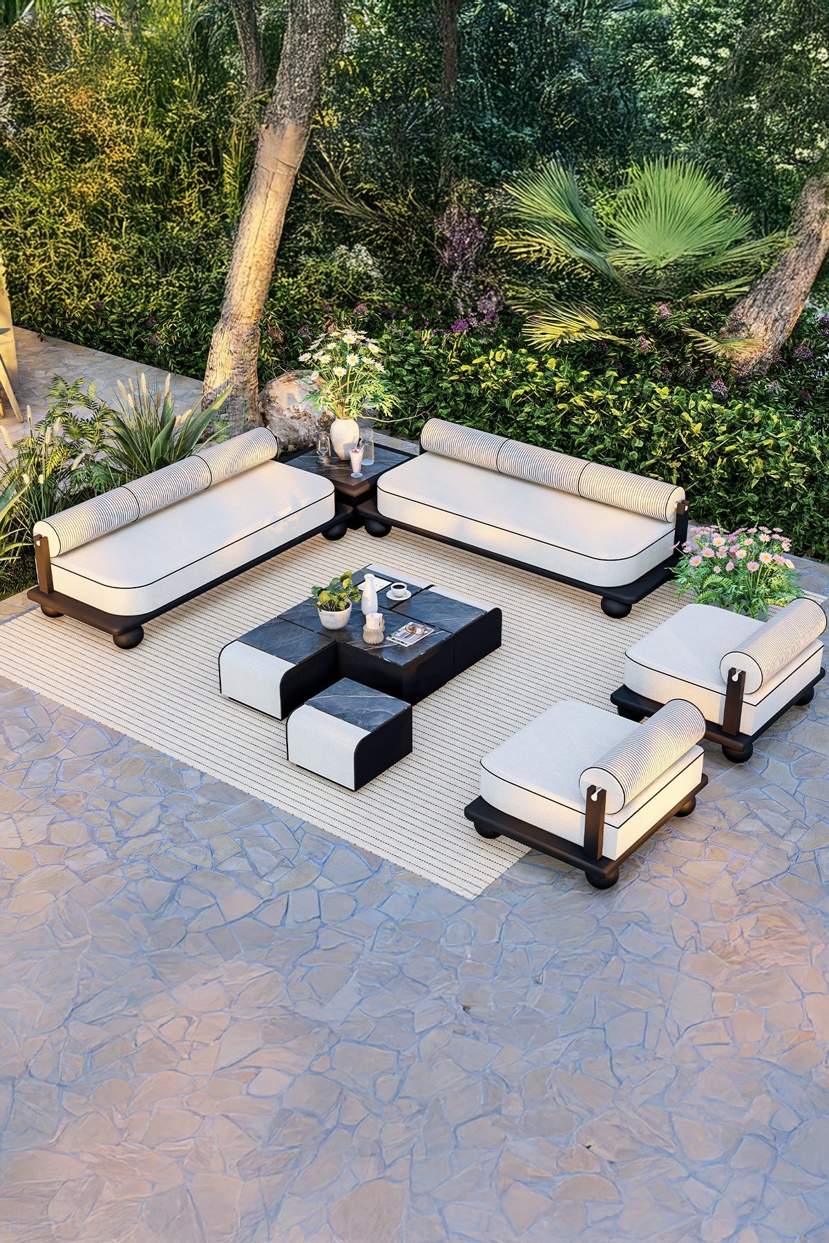 Outdoor patio furniture set with white cushions, black base, and modular coffee table on stone floor and rug.