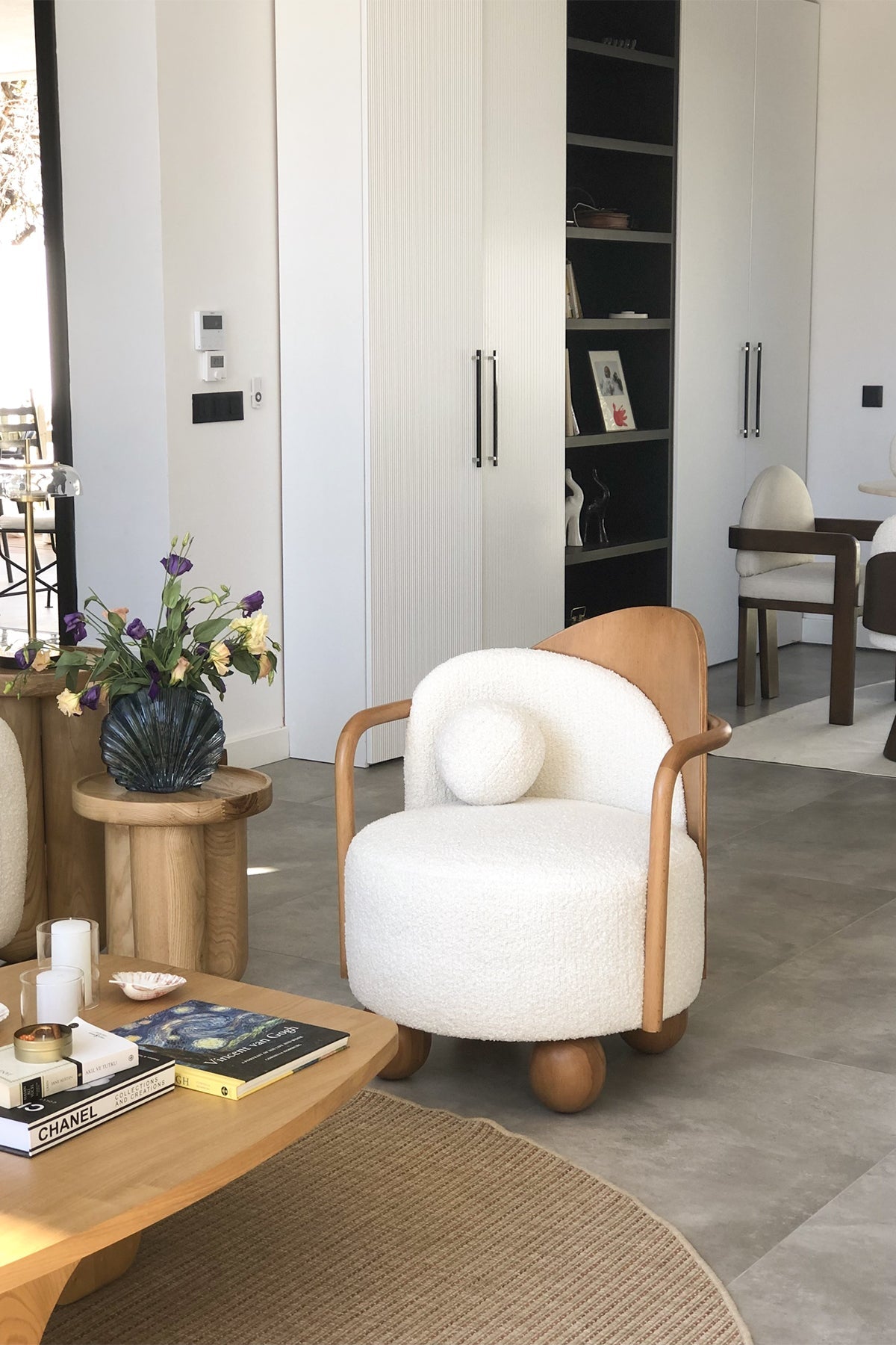 Living room scene with white boucle armchair and wooden coffee table