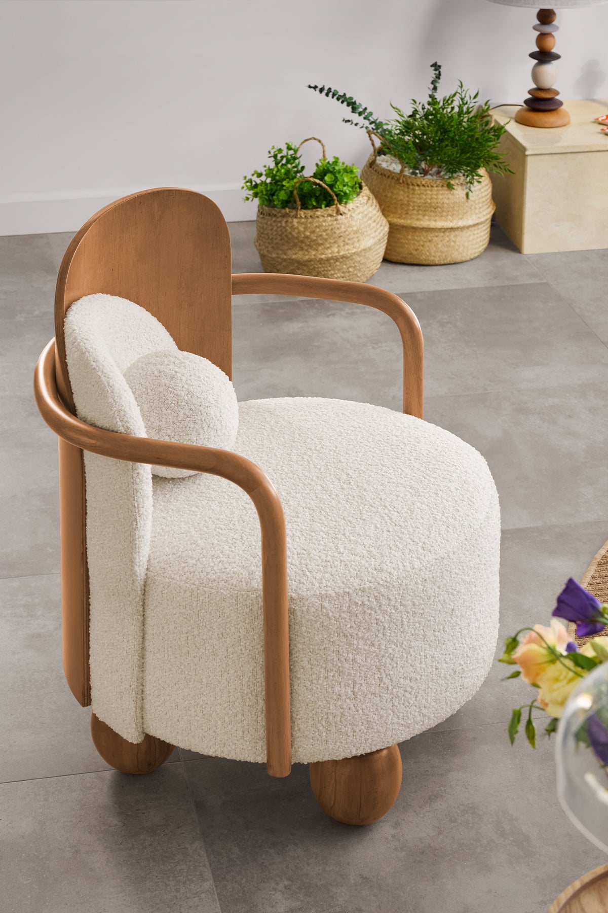 View of a white boucle armchair with wood frame and curved arms, cozy furniture.