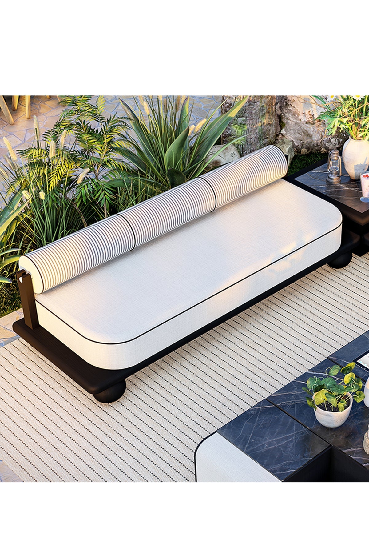 Outdoor daybed with white cushion and striped bolster pillow on patio.