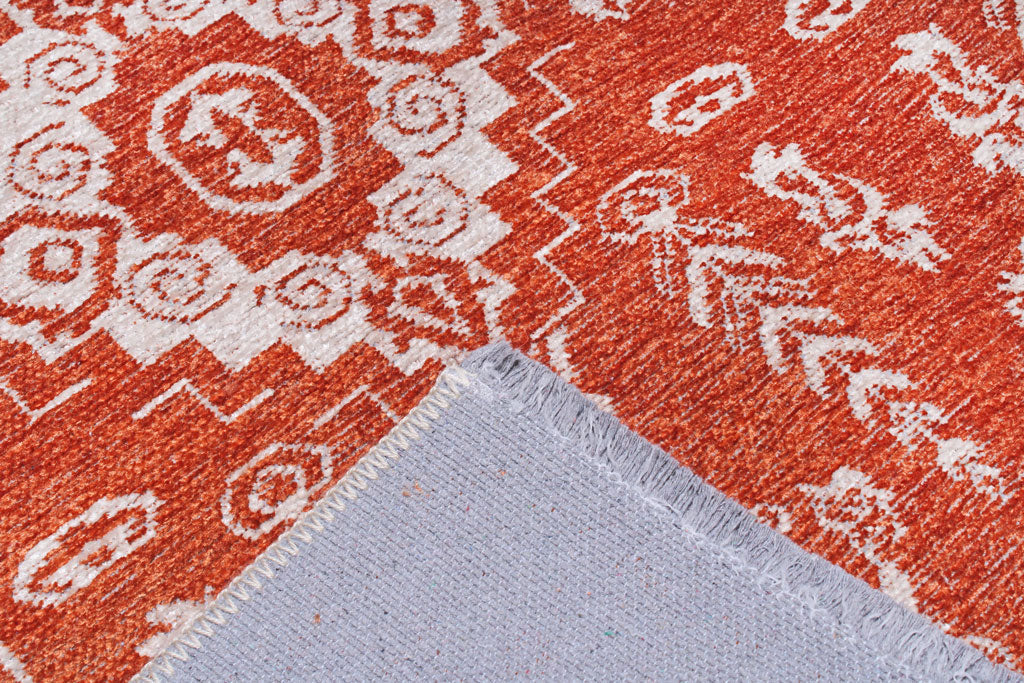 Close up of orange and white patterned rug with backing visible