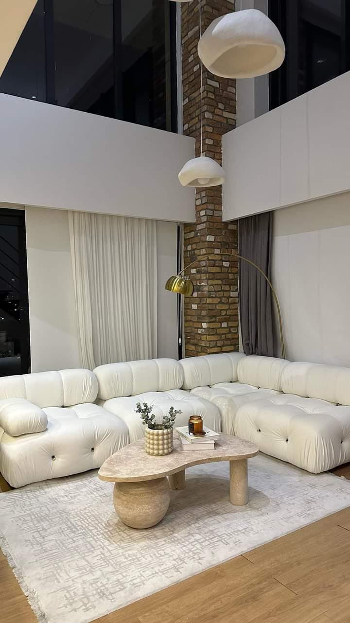 Modern living room with a modular white sofa, Luzione stone coffee table, stylish lighting, and area rug creating a luxurious and contemporary space