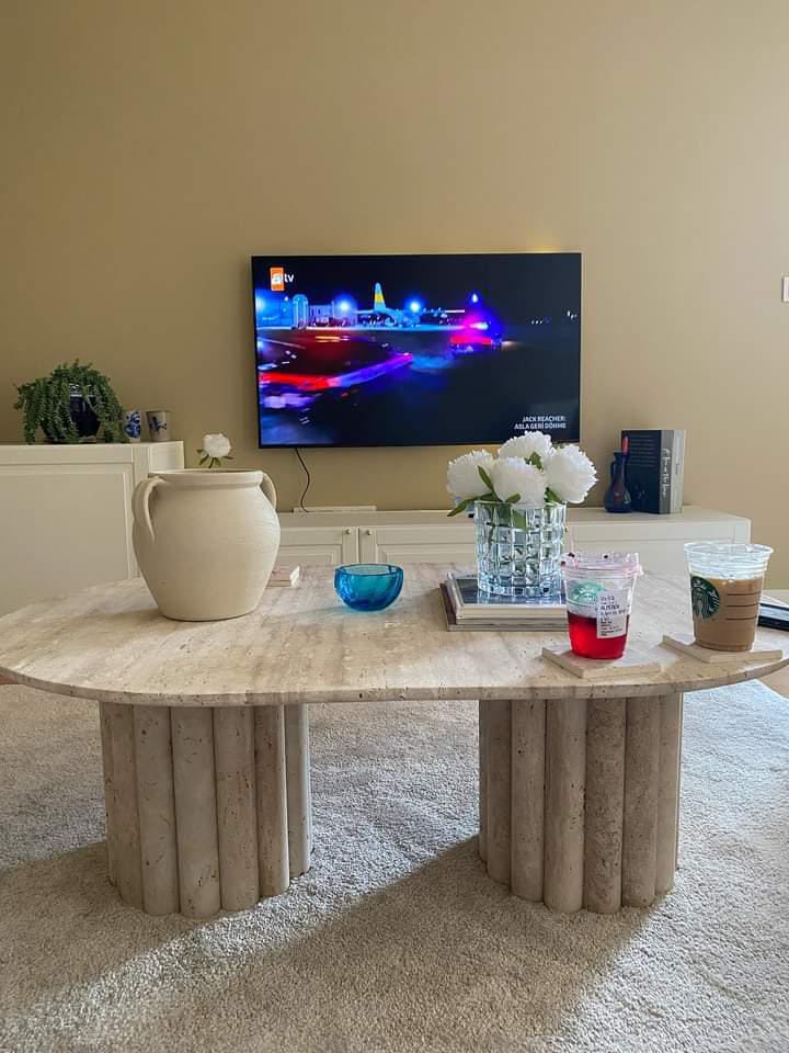Elevate your living room with the Luzione Travertine Coffee Table, a modern oval design with a natural stone finish and fluted pedestal base