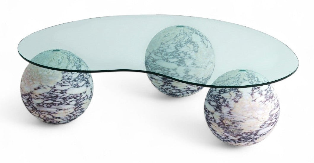 View of modern glass coffee table with three marble sphere bases. Modern furniture, glass table, marble spheres, coffee table, interior design.