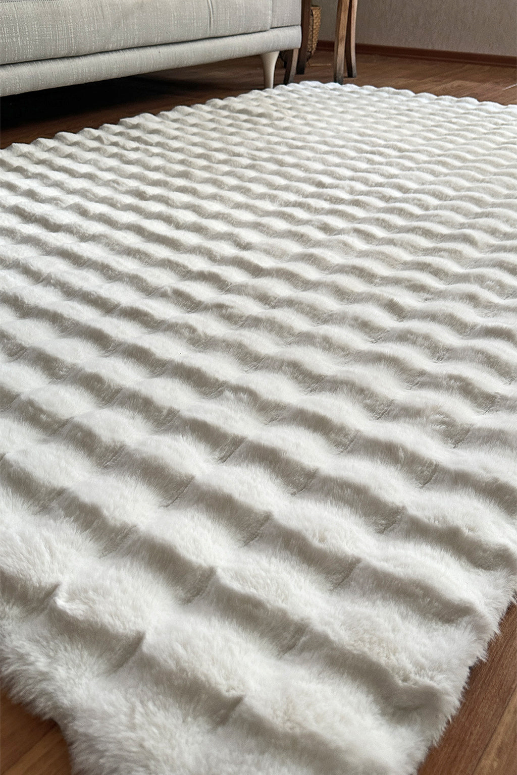 White faux fur rug with wavy texture on wood floor